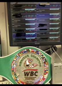 Carody's amateur WBC Champion belt in front of a screen displaying patient vitals at her job as a registered nurse