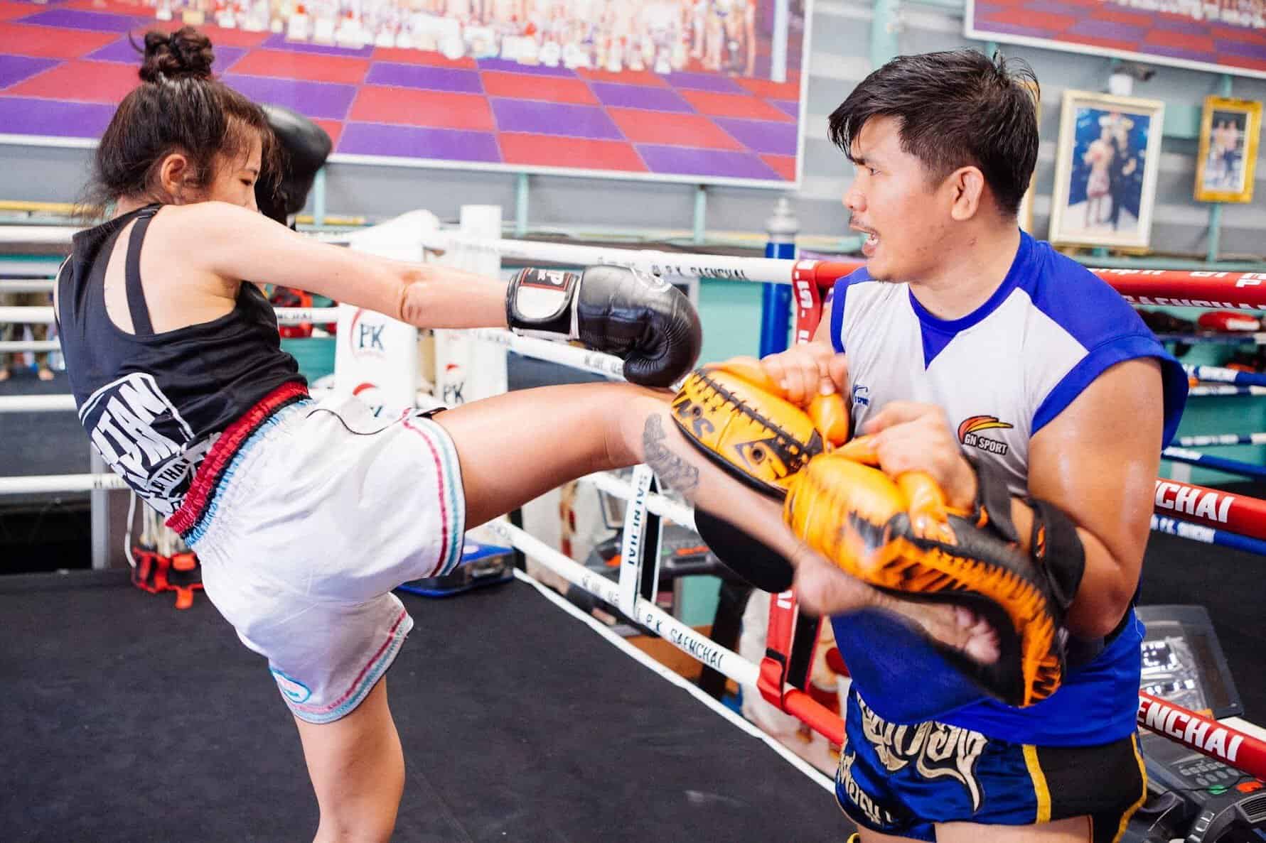 woman kicking pads with trainer