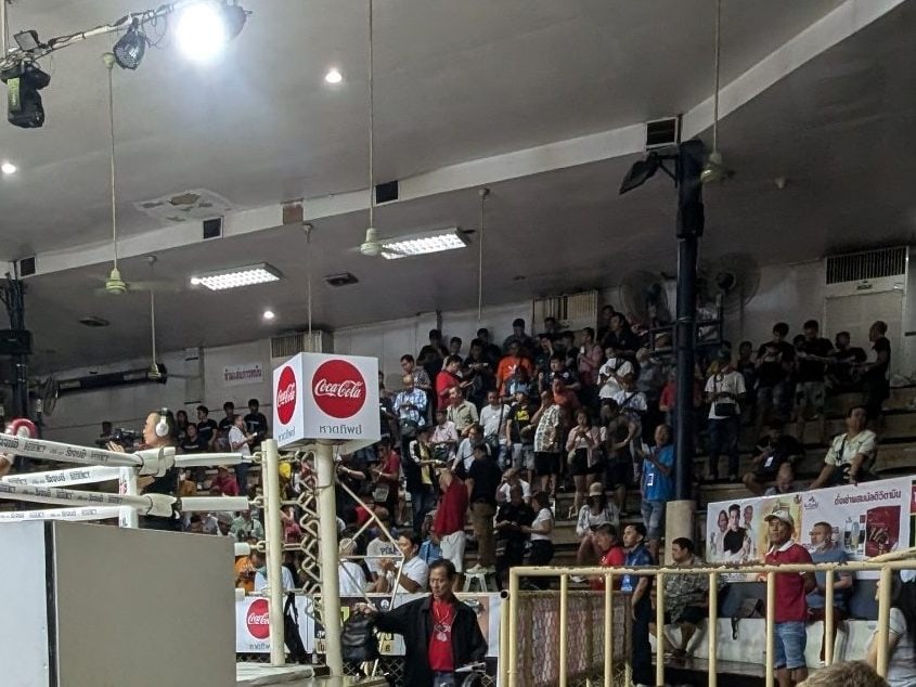boxer sitting waiting for turn at omnoi stadium. gamblers in background