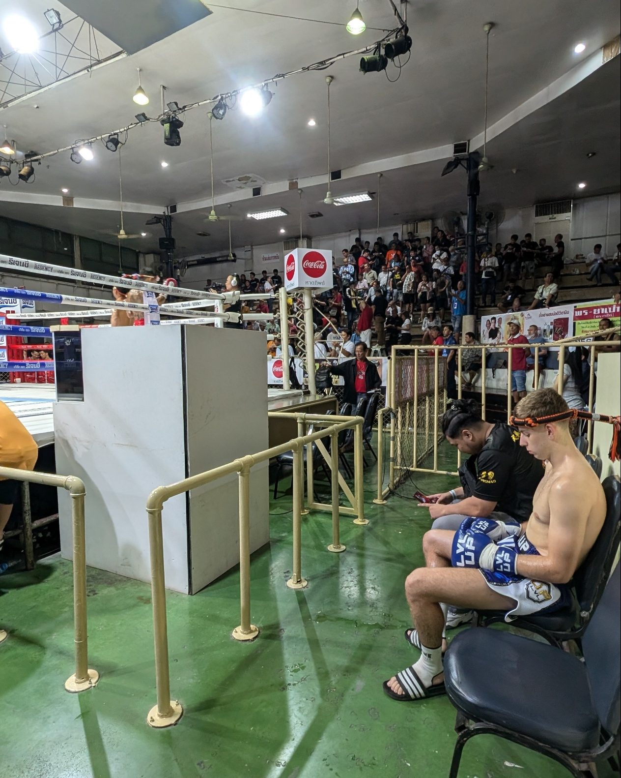 boxer sitting waiting for turn at omnoi stadium. gamblers in background