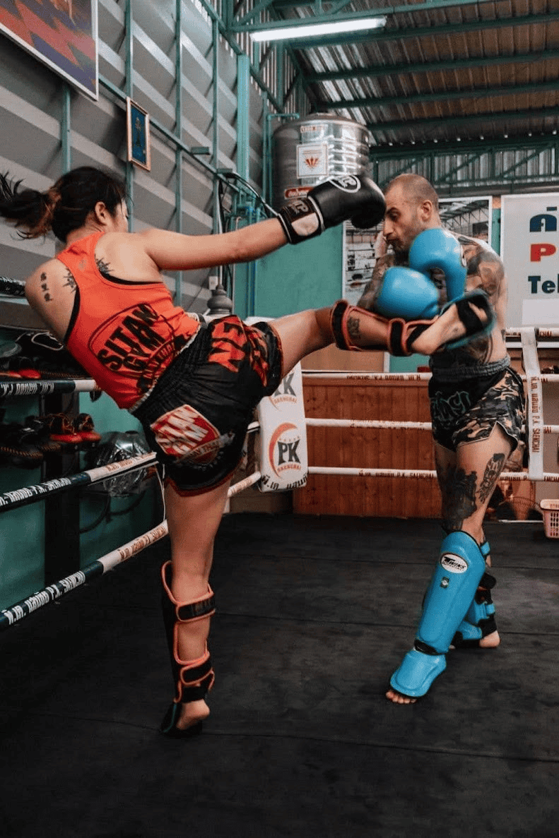Two people sparring in a Muay Thai gym in a ring