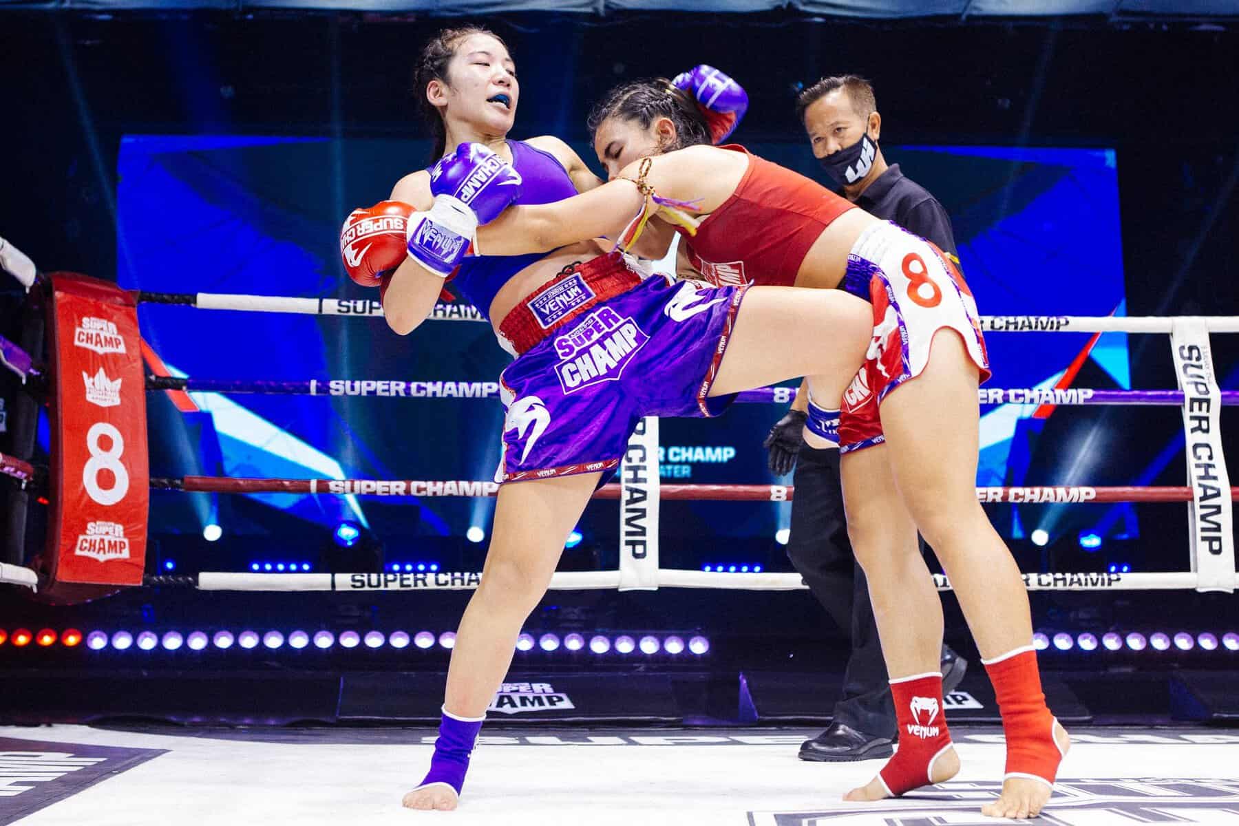 two women muay thai fighters, one throwing a knee
