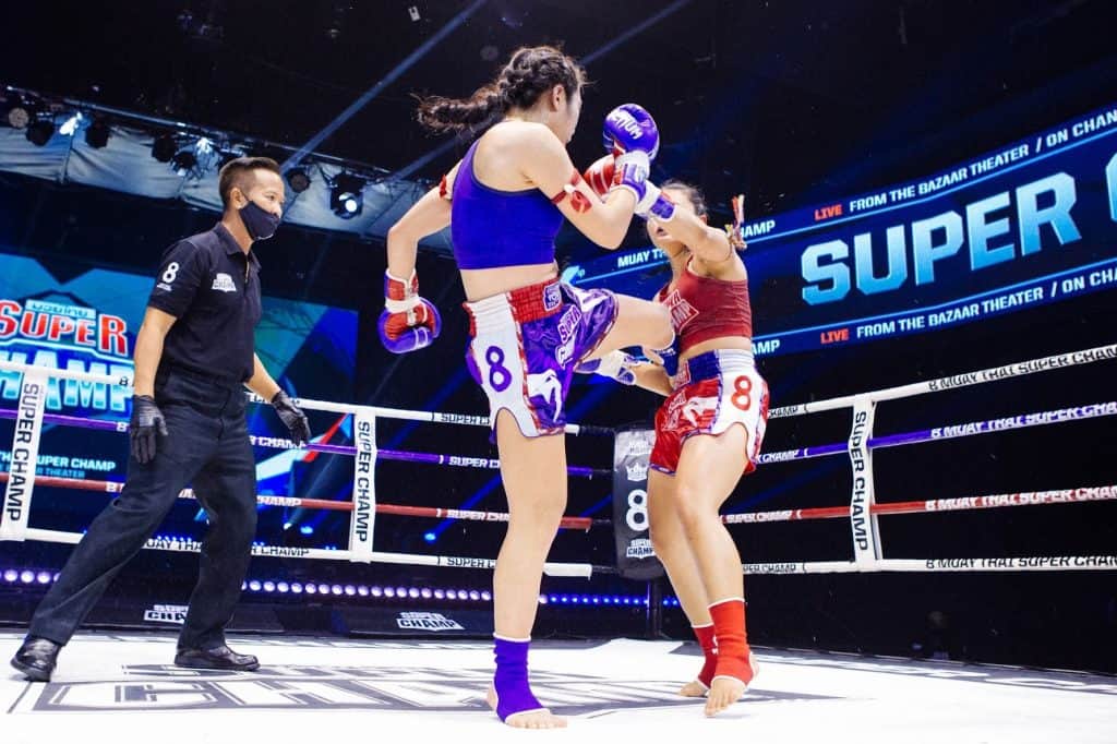 woman muay thai fighter throwing a leg kick at her opponent