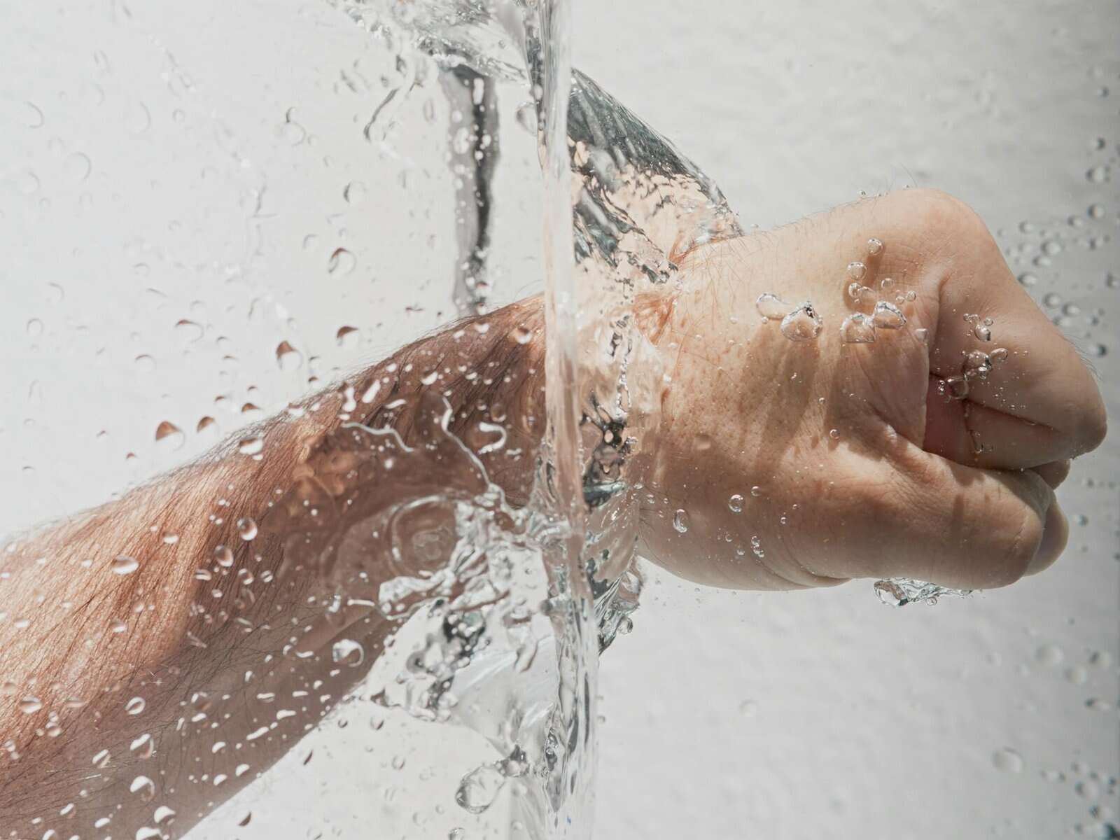 person s left fist punching water