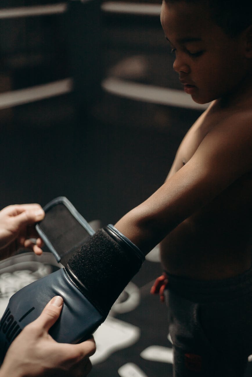topless man in black shorts holding black smartphone